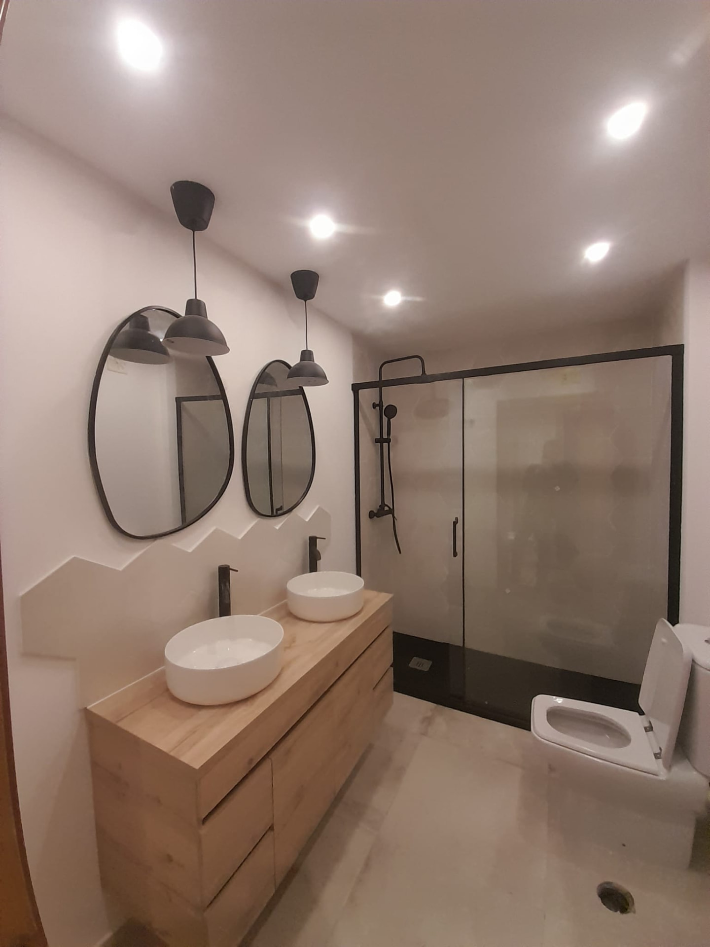 Casa de banho renovada com móvel suspenso, lavatórios de apoio e duche com vidro